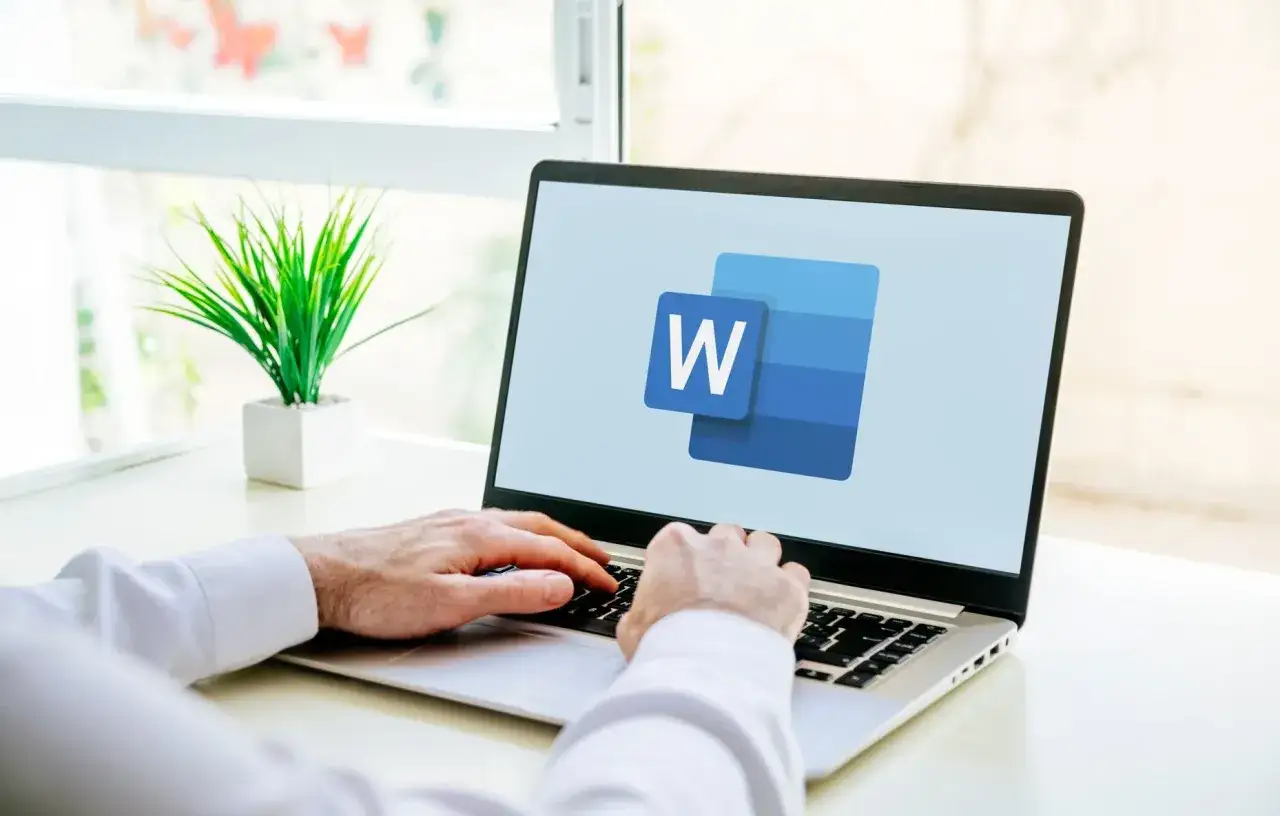 Ręce na klawiaturze laptopa z logo Word. Dowiedz się, jak usunąć tabelę w Word, by uporządkować dokument.