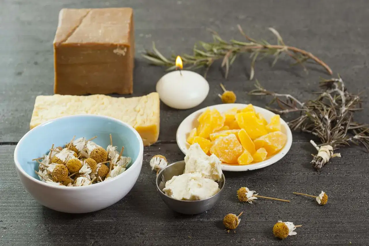 Bienenwachs, Kräuter und Seife für DIY-Kosmetik auf dunklem Holztisch.