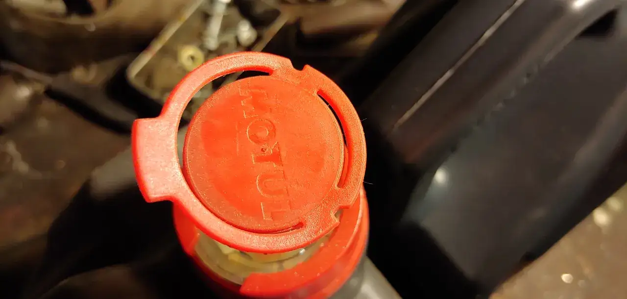 Czerwona nakrętka z logo Motul na opakowaniu oleju silnikowego.