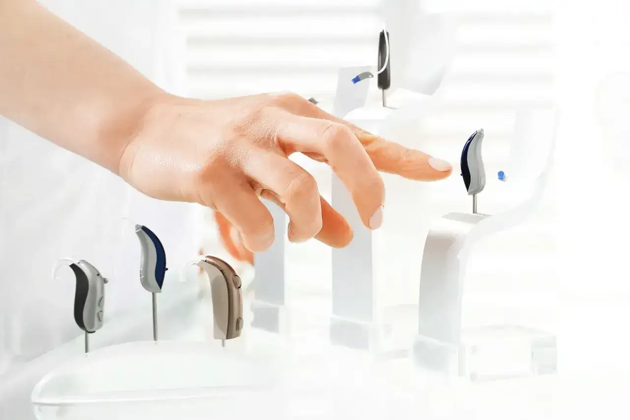 Dłoń wybiera aparat słuchowy. Dowiedz się, komu należy się aparat słuchowy za darmo i jakie są kryteria.