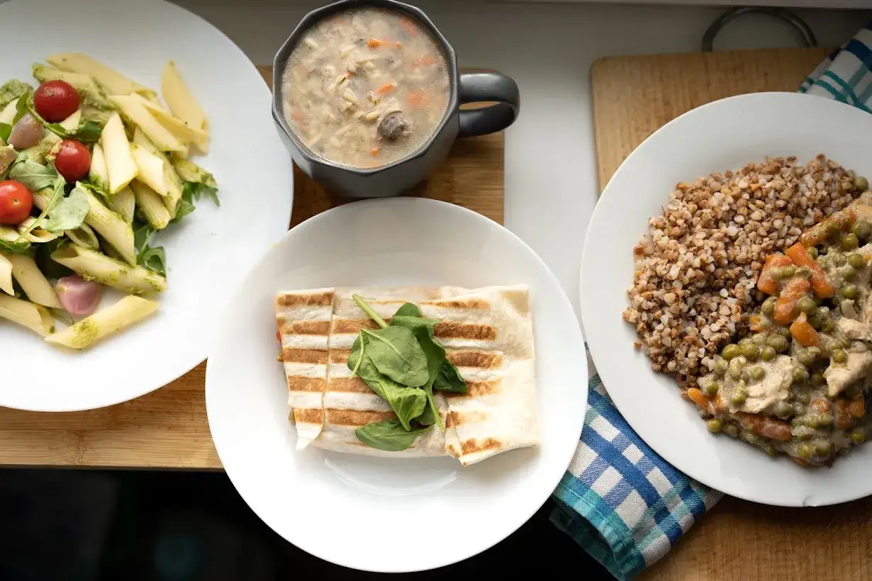 Pyszne dania: makaron z pomidorkami, wrap ze szpinakiem, zupa i kasza z gulaszem. To catering jak u mamy, pełen smaku i domowej roboty.