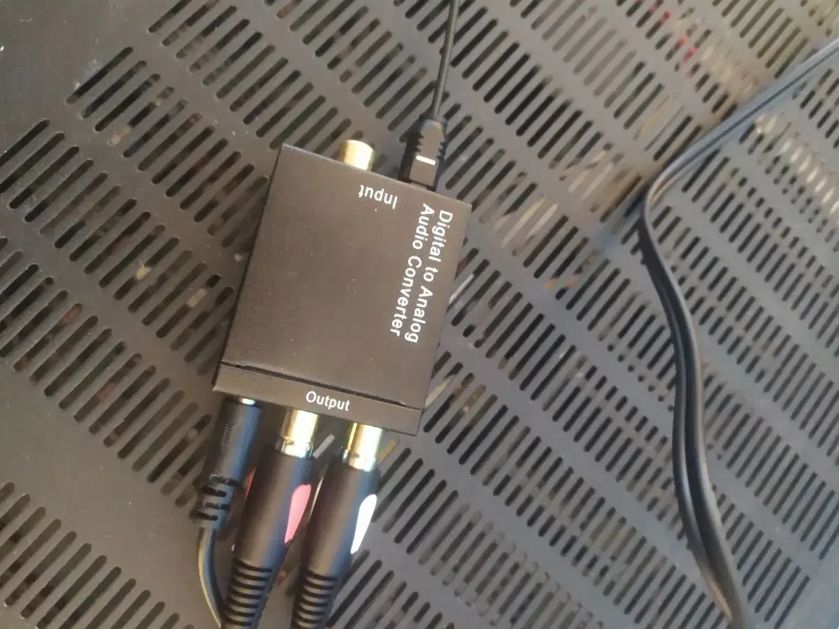 Konwerter cyfrowo-analogowy audio z podłączonymi kablami RCA i optycznym.