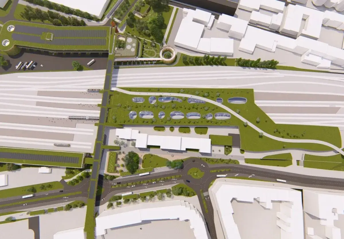 Nowoczesny, zintegrowany węzeł przesiadkowy z zielonymi dachami, torami kolejowymi, budynkami i drogami.