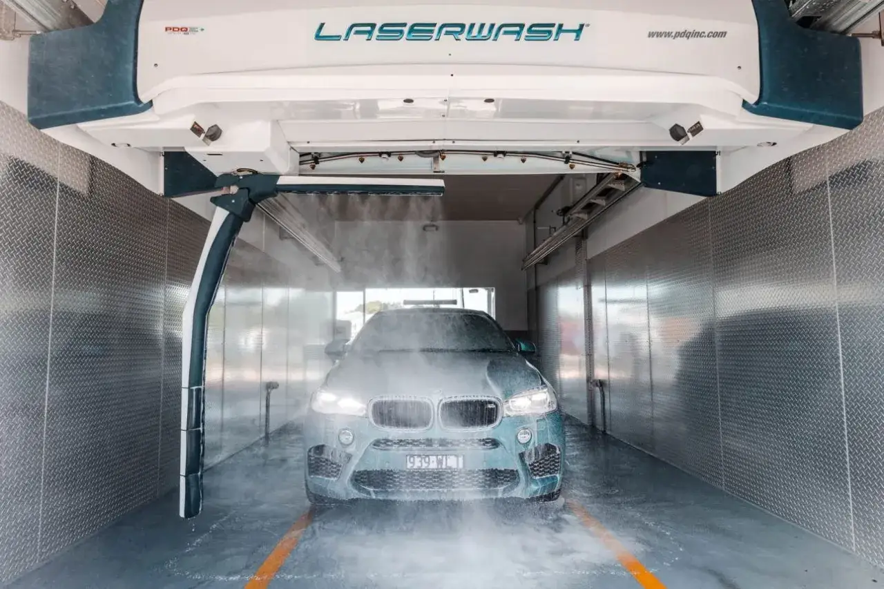 Samochód w myjni bezdotykowej, spryskiwany wodą.