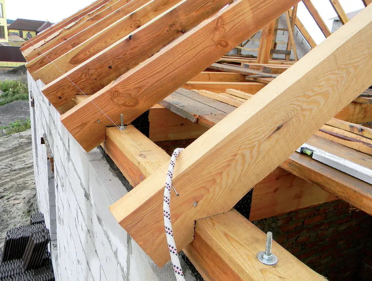 Solidne mocowanie krokwi do murłaty zapewnia stabilność konstrukcji dachu. Widać śruby i drewniane elementy.