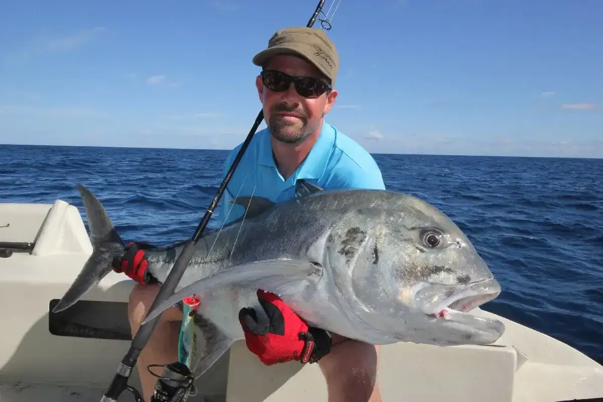 Szczęśliwy wędkarz z wielką rybą na łodzi. To świetny przykład, na co łowić ryby w Chorwacji, gdy wybierasz się na morskie przygody.