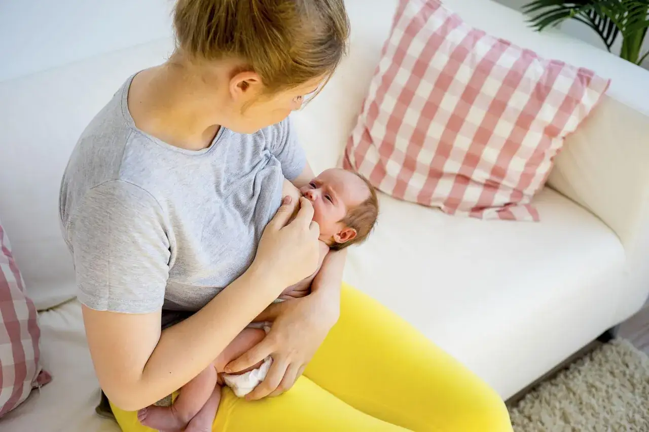 Mama karmi piersią noworodka. To piękny moment, kiedy pojawia się nawał pokarmu.