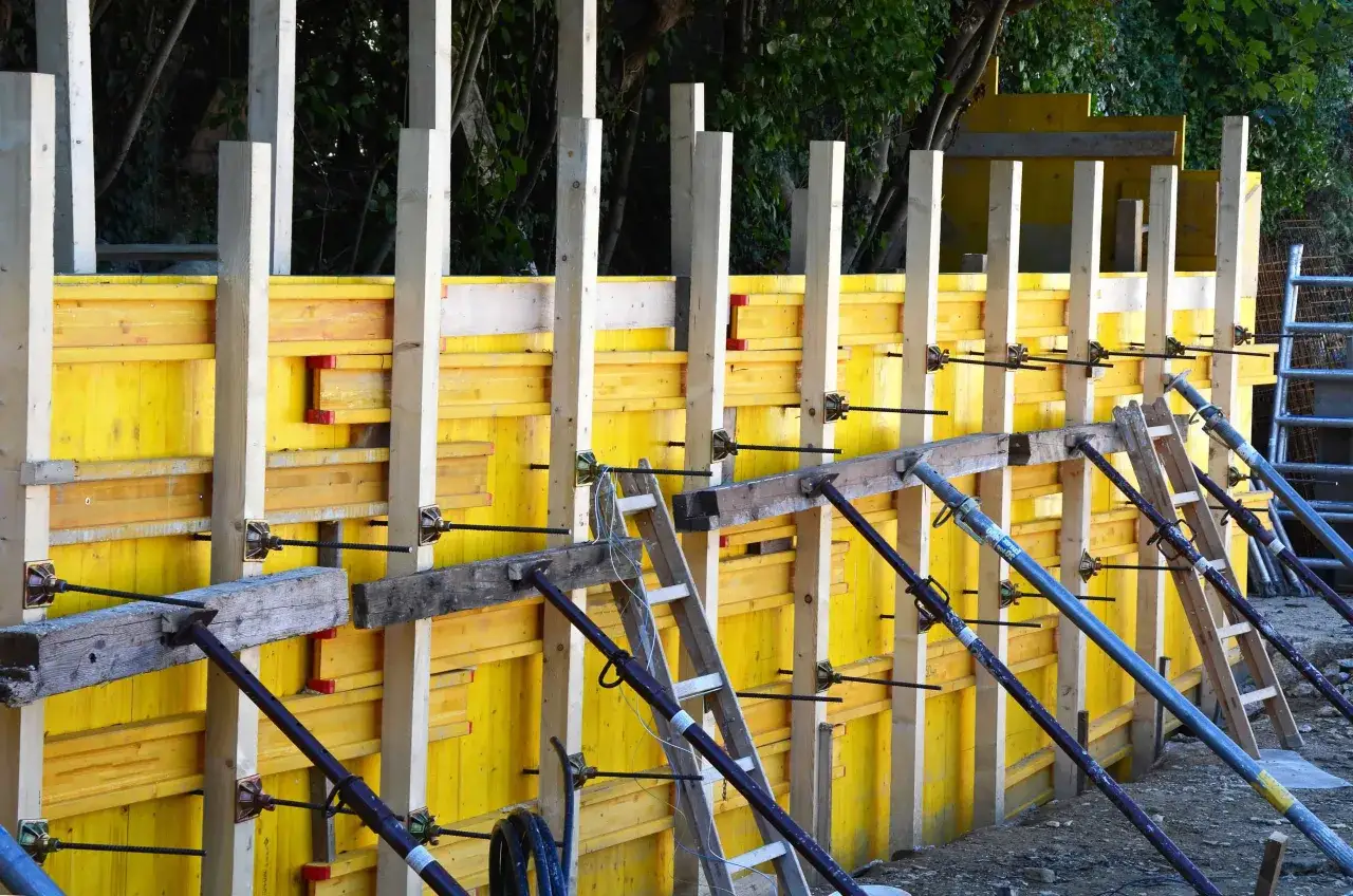 Szalunek co to? Żółte płyty i drewniane słupy tworzą konstrukcję do wylewania betonu.