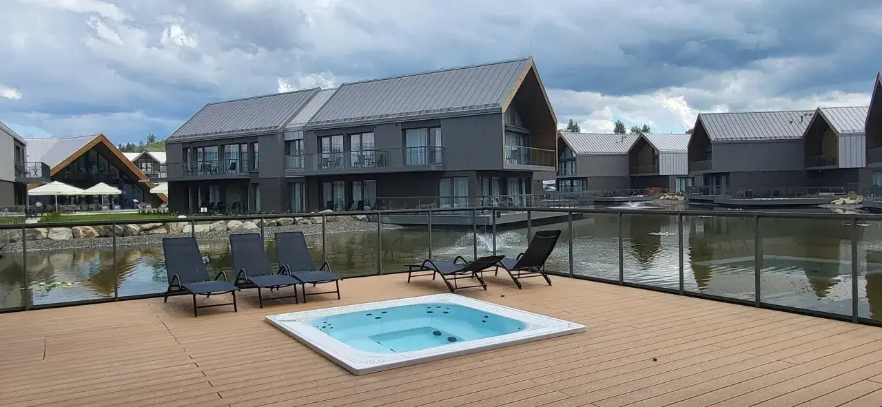 Relaks przy jacuzzi i basenie z widokiem na nowoczesne domki nad wodą. Idealne miejsce na wypoczynek w stylu termy Karkonosze.
