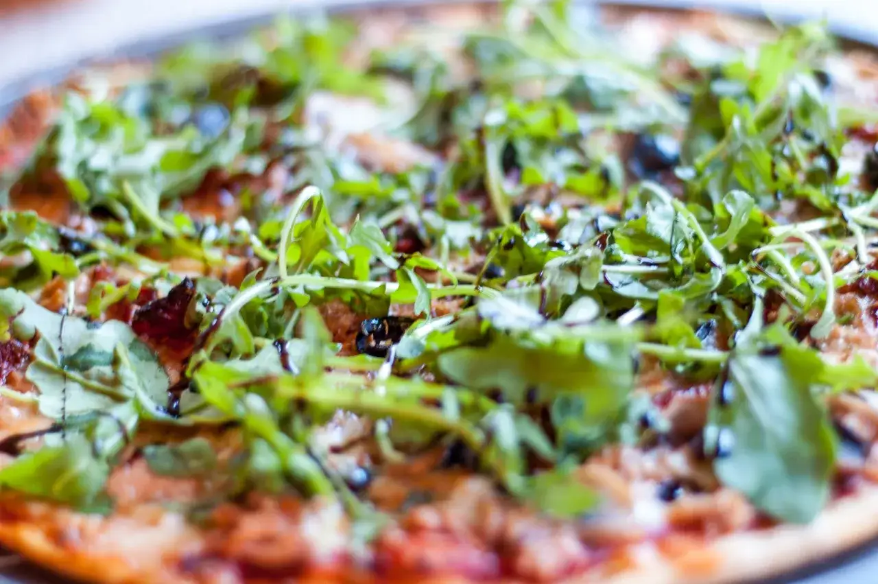 Pyszna pizza z tuńczykiem, rukolą i oliwkami, polana sosem balsamicznym. Idealna na szybki obiad.