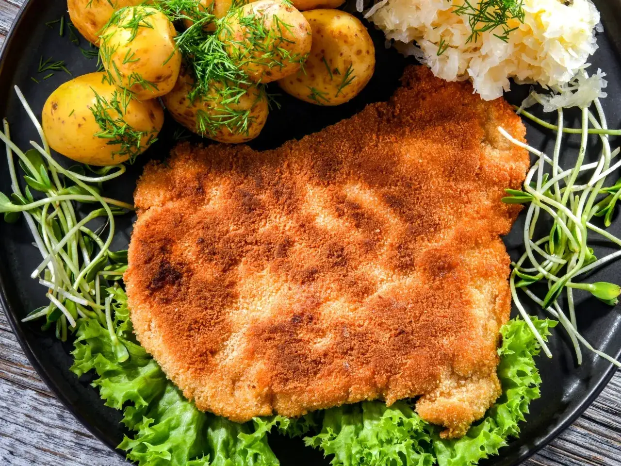 Chrupiący schabowy w panko, podany z młodymi ziemniaczkami, surówką i kiełkami. Pyszny obiad gotowy!