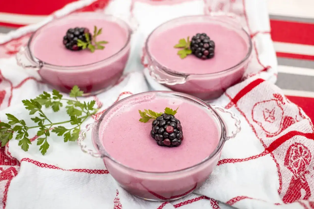 Różowa pianka z galaretki, udekorowana jeżyną i natką pietruszki, w szklanych pucharkach. Idealna na deser, łatwa do zrobienia.