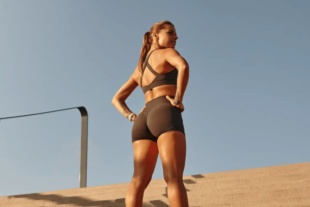 Kobieta w sportowym stroju, z rękami na biodrach, zastanawia się, jakie tętno do spalania tłuszczu jest najlepsze.