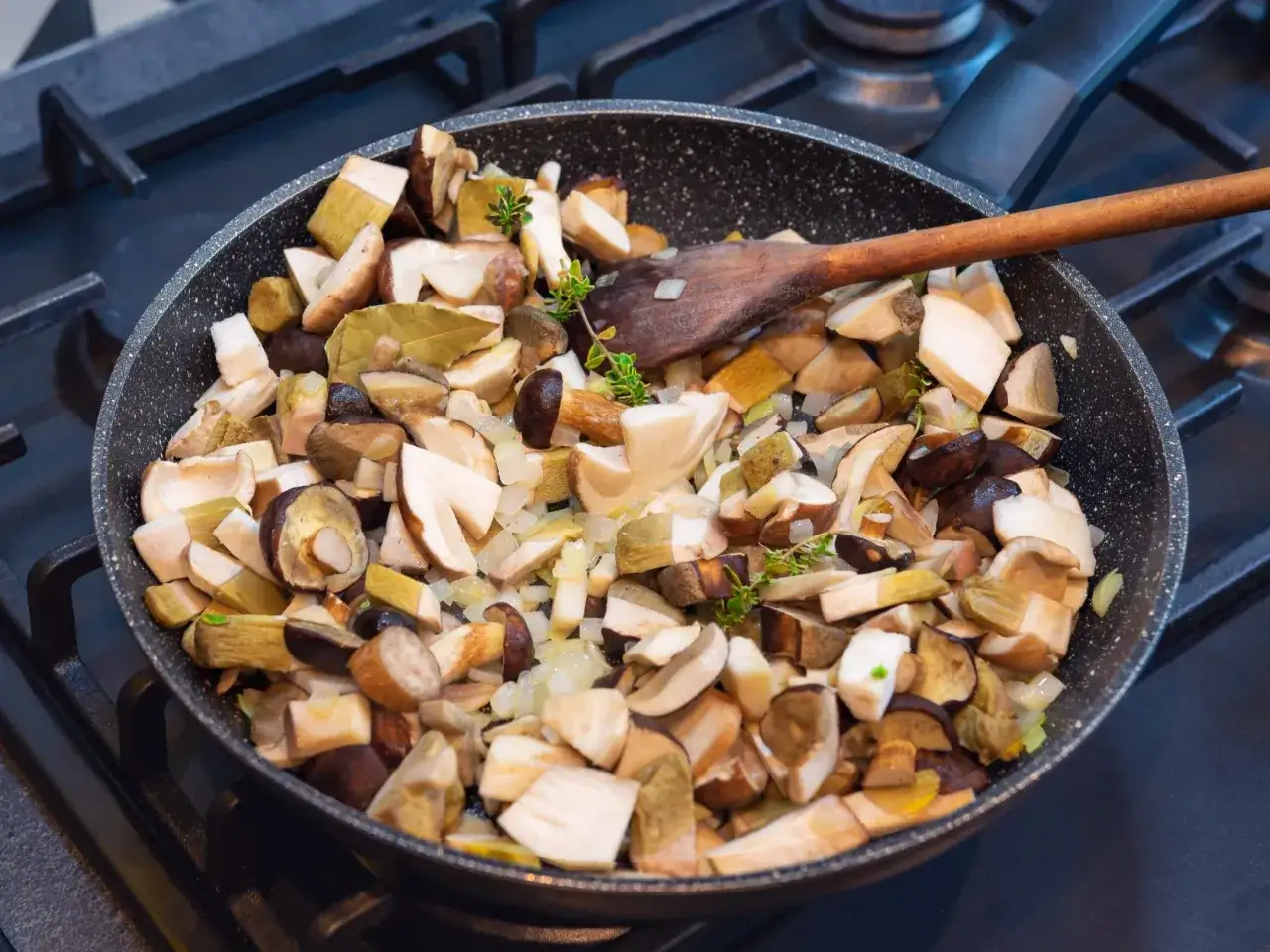 Na patelni podsmażane są grzyby leśne z cebulką i ziołami, przygotowywany pyszny sos grzybowy.