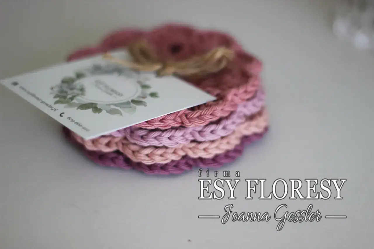 Stosik ręcznie robionych, szydełkowych podkładek pod kubek w odcieniach różu i fioletu. Na wierzchu wizytówka firmy ESY FLORY.