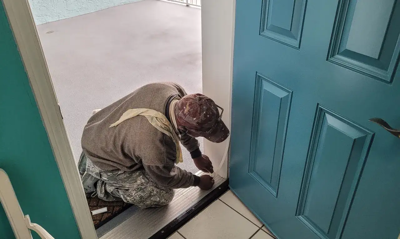 Pracownik montuje uszczelkę, co jest ważnym elementem uzasadnienia wymiany drzwi wejściowych na nowe, zapewniające lepszą izolację.