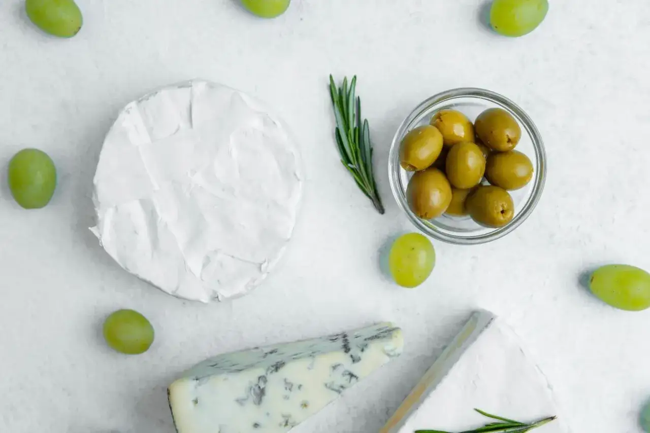 Ser brie, pleśniowy i winogrona otaczają miseczkę z oliwkami. Czy oliwki są lekkostrawne?