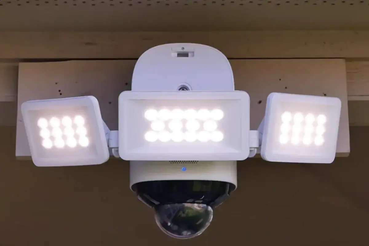 Biały naświetlacz LED z trzema panelami i kamerą kopułkową.
