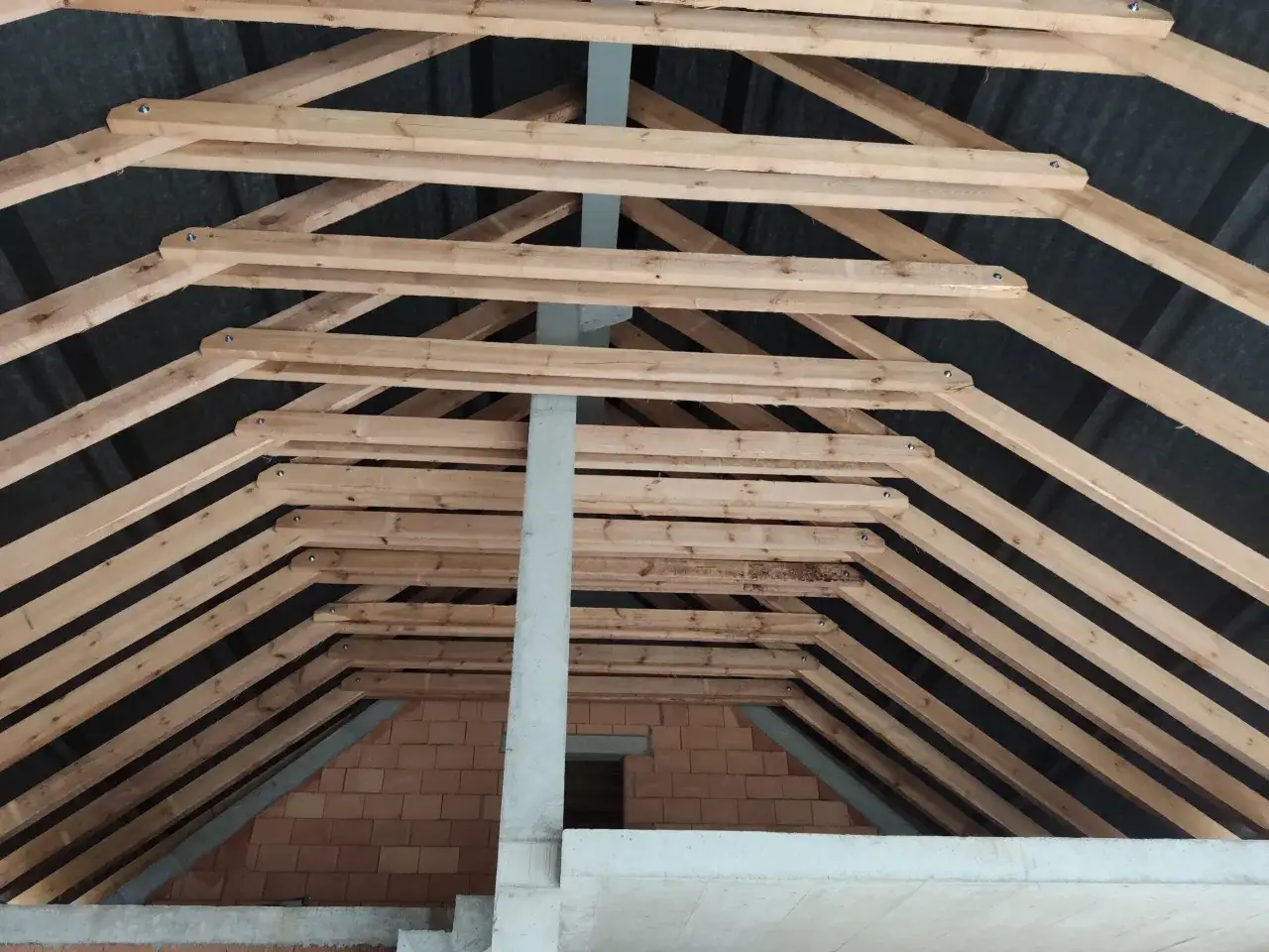 Drewniana konstrukcja dachu, ukazująca różne rodzaje więźby dachowej w trakcie budowy.