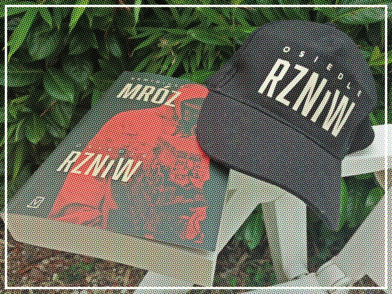 Książka "Mróz RZNiW" i czapka z napisem "Osiedle RZNiW" na tle zieleni.