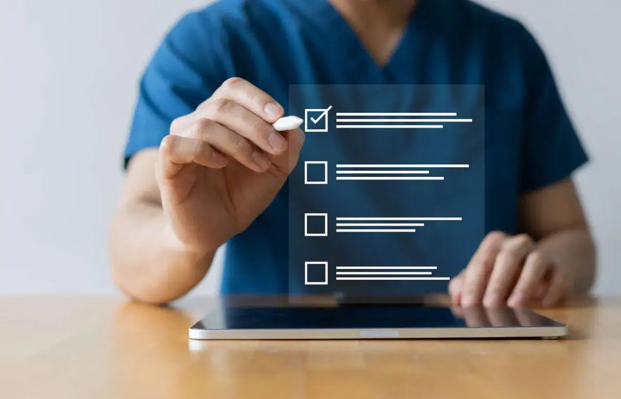 Dłoń zaznacza ptaszkiem pierwszy element na liście kontrolnej wyświetlanej na ekranie tabletu.