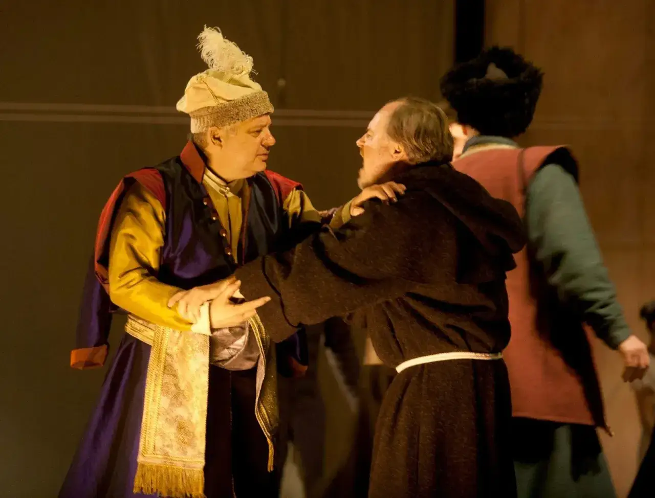 Dwóch mężczyzn w strojach teatralnych, jeden w barwnym, drugi w habicie, w dramatycznym uścisku. Czy szlachetnymi uczynkami można odkupić ciężką winę?