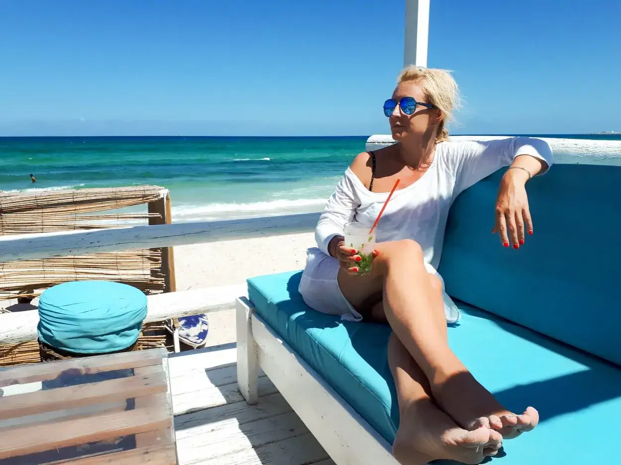 Kobieta z drinkiem na plaży w Tunezji. Czy Tunezja jest bezpieczna dla kobiet? Tak, można tu odpoczywać.