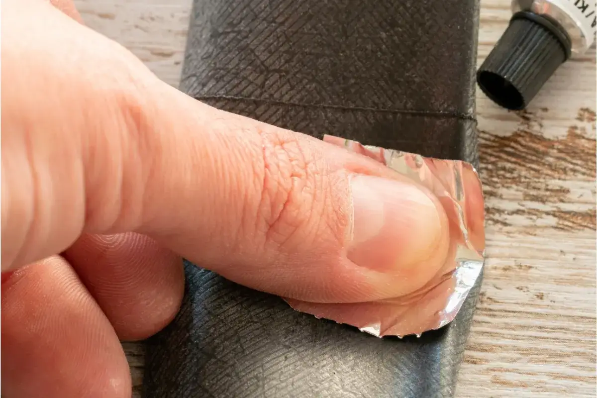 Palec dociska łatkę do dętki rowerowej, pokazując, jak wymienić dętkę w rowerze.