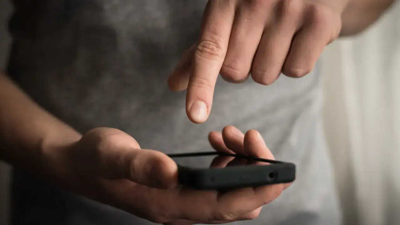 Dłoń trzyma smartfon, na którym uruchomiony jest dyktafon w telefonie.