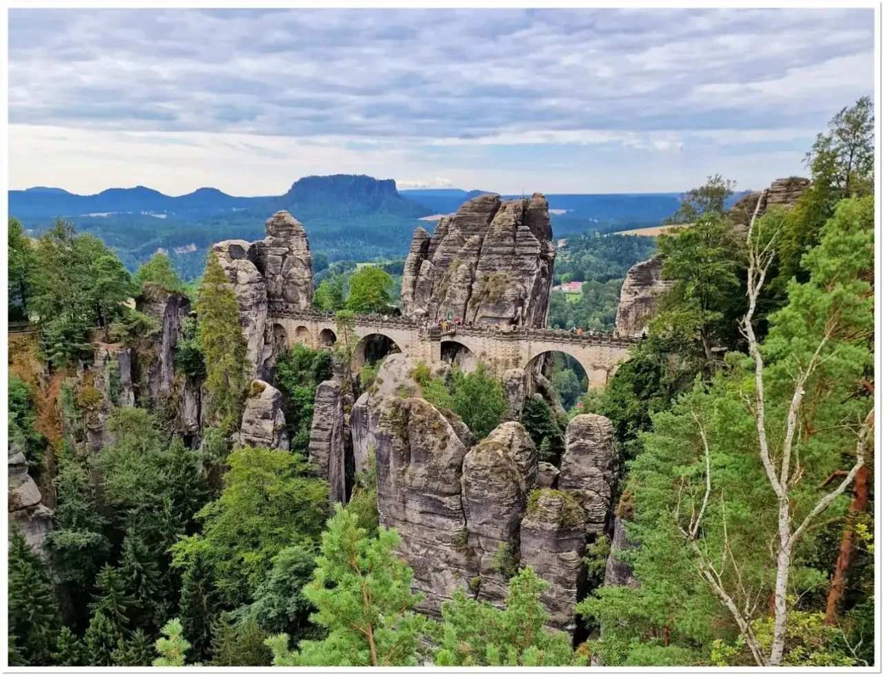 Kamienny most Basteibrücke w Szwajcarskiej Saksonii, łączący skalne baszty pośród zielonych lasów i gór.