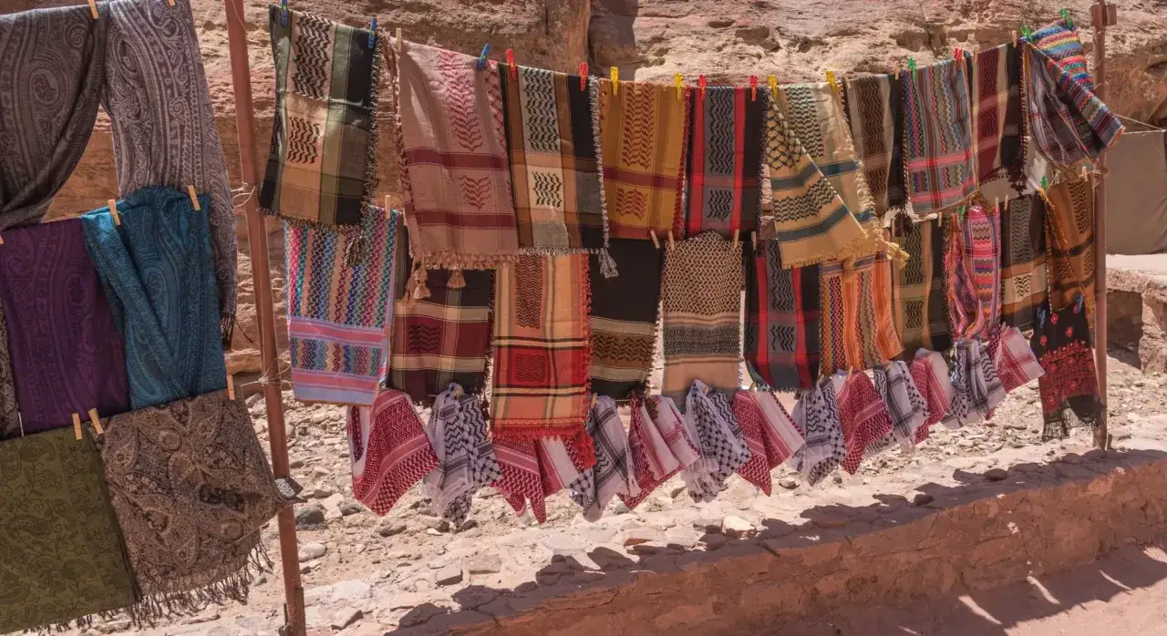 Kolorowe chusty i szale wiszą na sznurku, idealne pamiątki, które warto przywieźć z Jordanii.