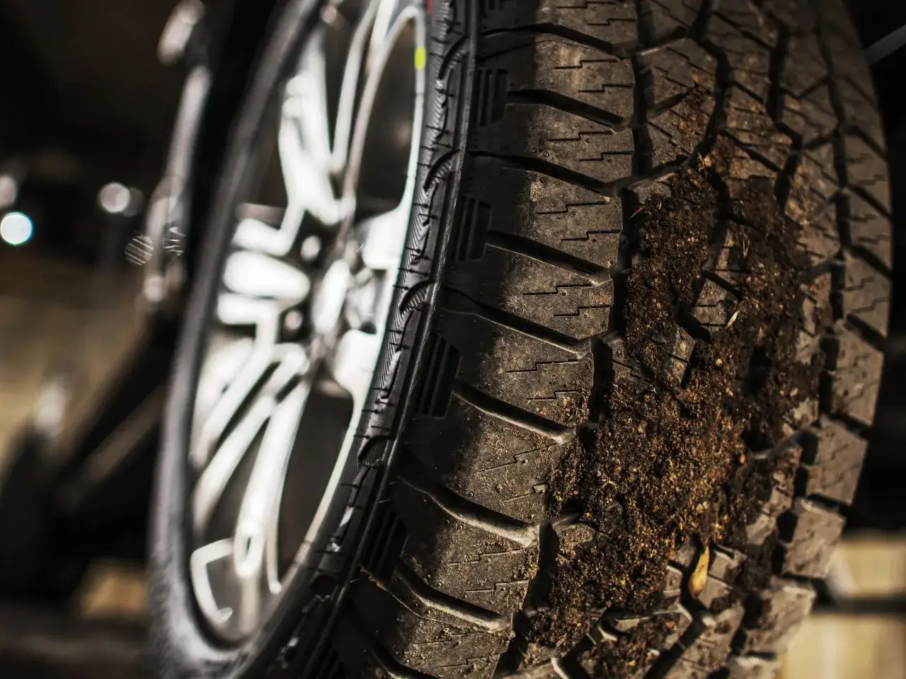 Zbliżenie na brudną oponę wielosezonową z felgą w tle.