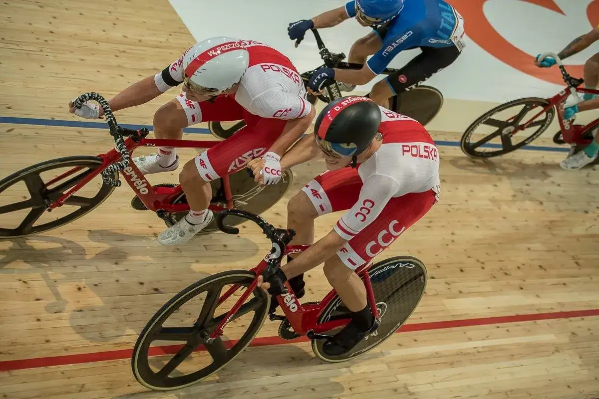 Wyścig kolarski madison. Dwóch kolarzy w biało-czerwonych strojach jedzie na torze.