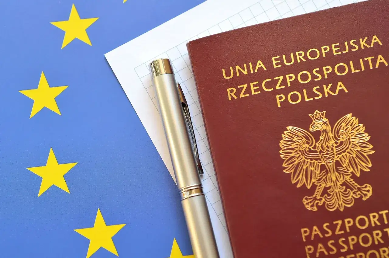Polski paszport, długopis i flaga Unii Europejskiej.