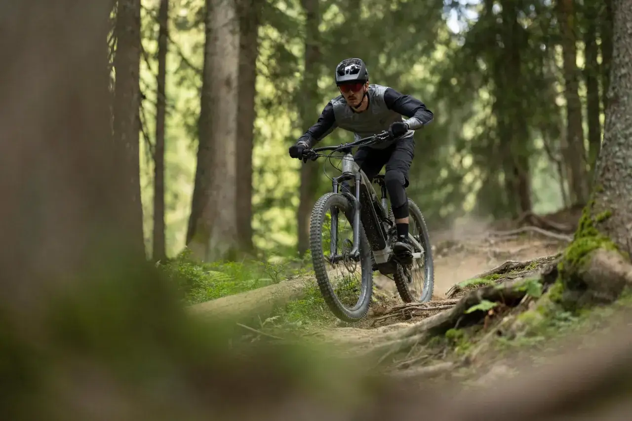 Rowerzysta w kasku i okularach zjeżdża po wyboistej leśnej ścieżce. To właśnie jest **co to enduro** – jazda po trudnym terenie.
