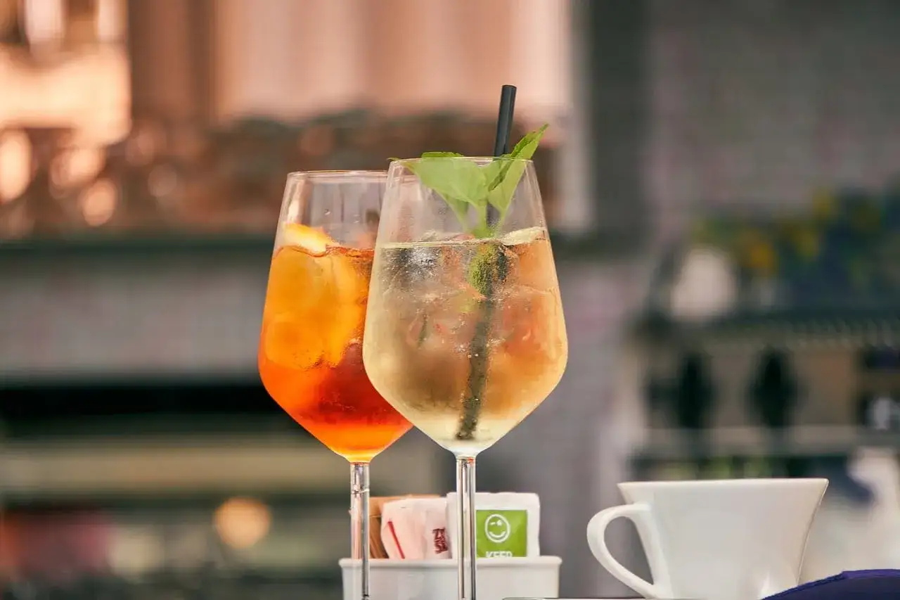 Dwa drinki z lodem i owocami, jeden pomarańczowy, drugi jasny. Czy warto kupować drogie giny do drinków mieszanych z owocami?