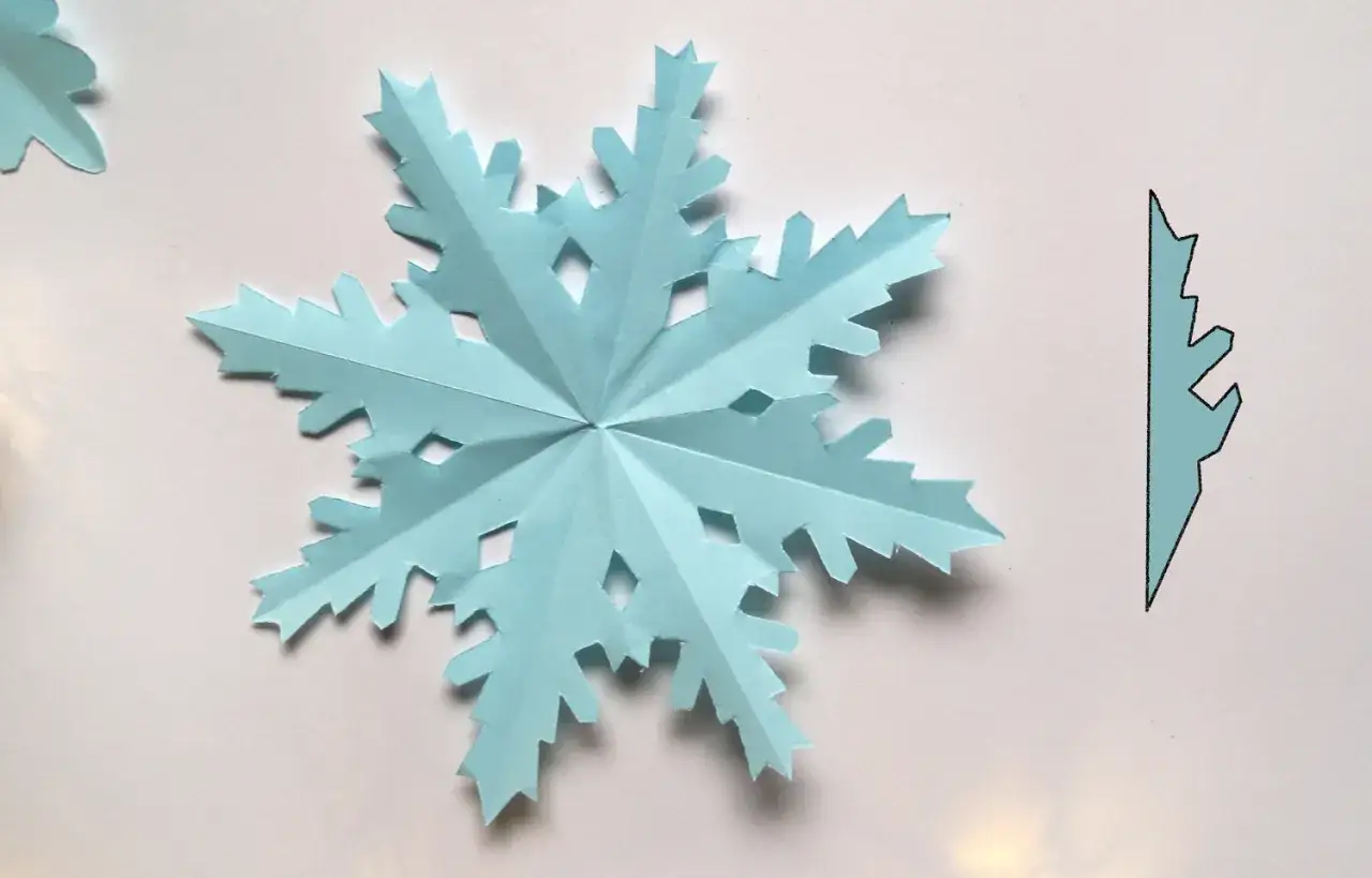 Delikatne, błękitne gwiazdki z papieru, jak zimowe ozdoby, gotowe do zawieszenia. Obok wycięty fragment do stworzenia kolejnych.