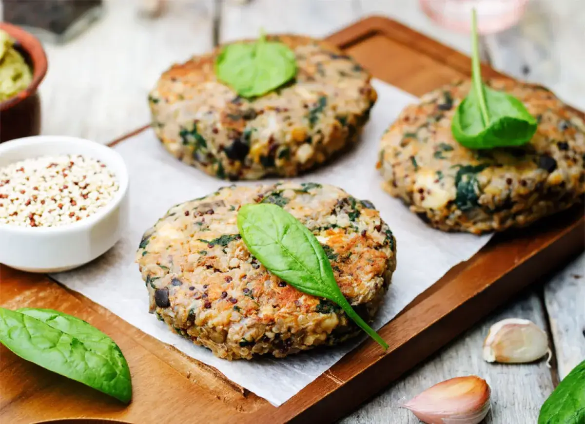Pyszne kotleciki z komosy ryżowej i szpinaku, idealne na obiad wege. Obok miseczka z komosą i czosnek.
