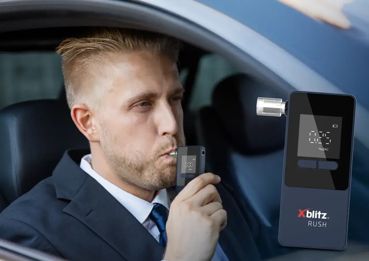 Mężczyzna w garniturze dmucha w alkomat w samochodzie.