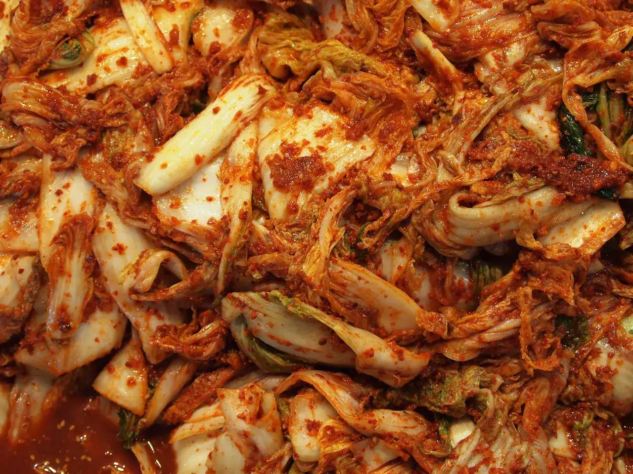 Zbliżenie na świeże, pikantne kimchi z kapusty pekińskiej, pokryte czerwoną pastą chili.