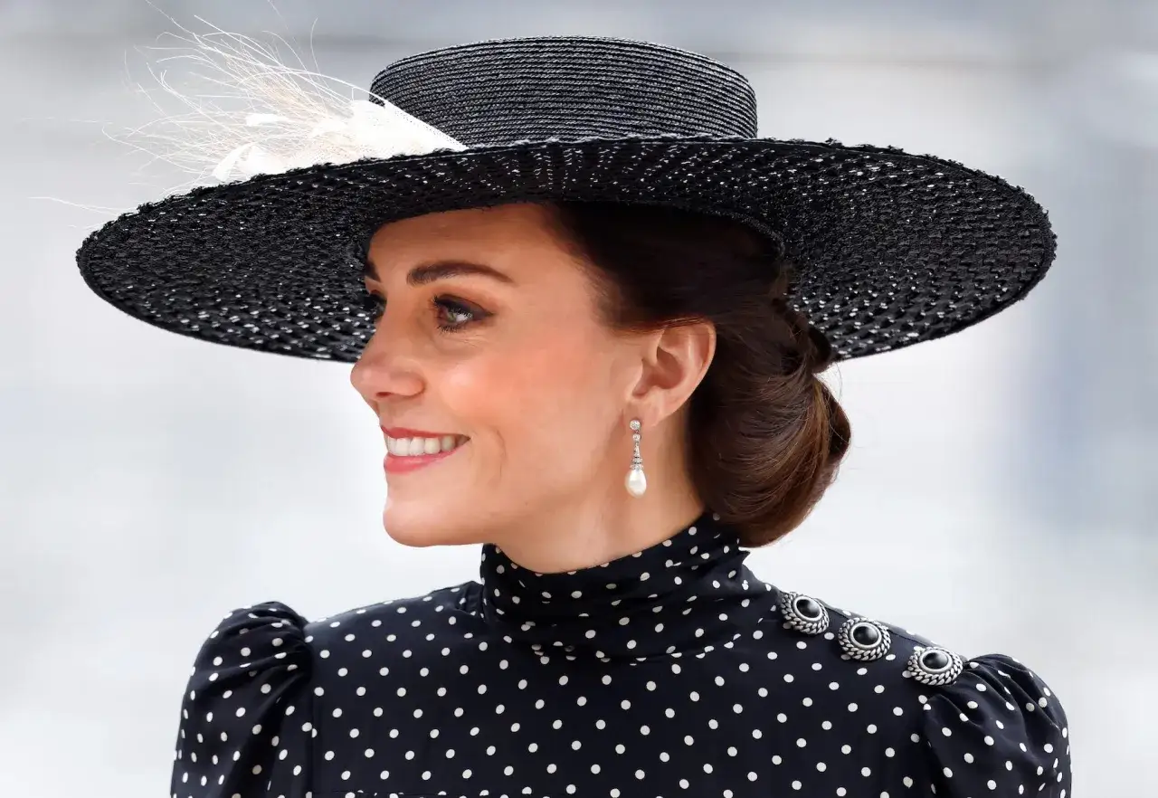 Księżna Kate w eleganckiej, czarno-białej sukience w grochy i stylowym kapeluszu.