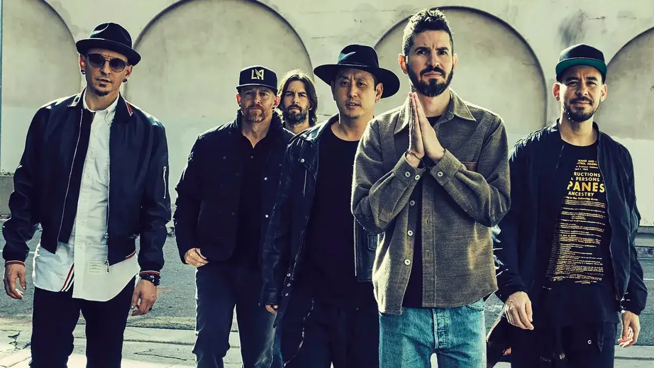 Sechs Männer der Band Linkin Park stehen nebeneinander, einige tragen Hüte und Jacken.