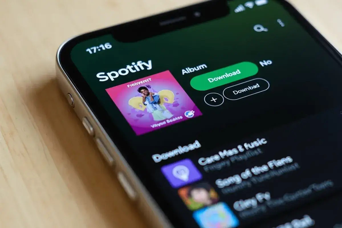 Ekran telefonu z aplikacją Spotify, widoczna okładka albumu i przyciski pobierania.