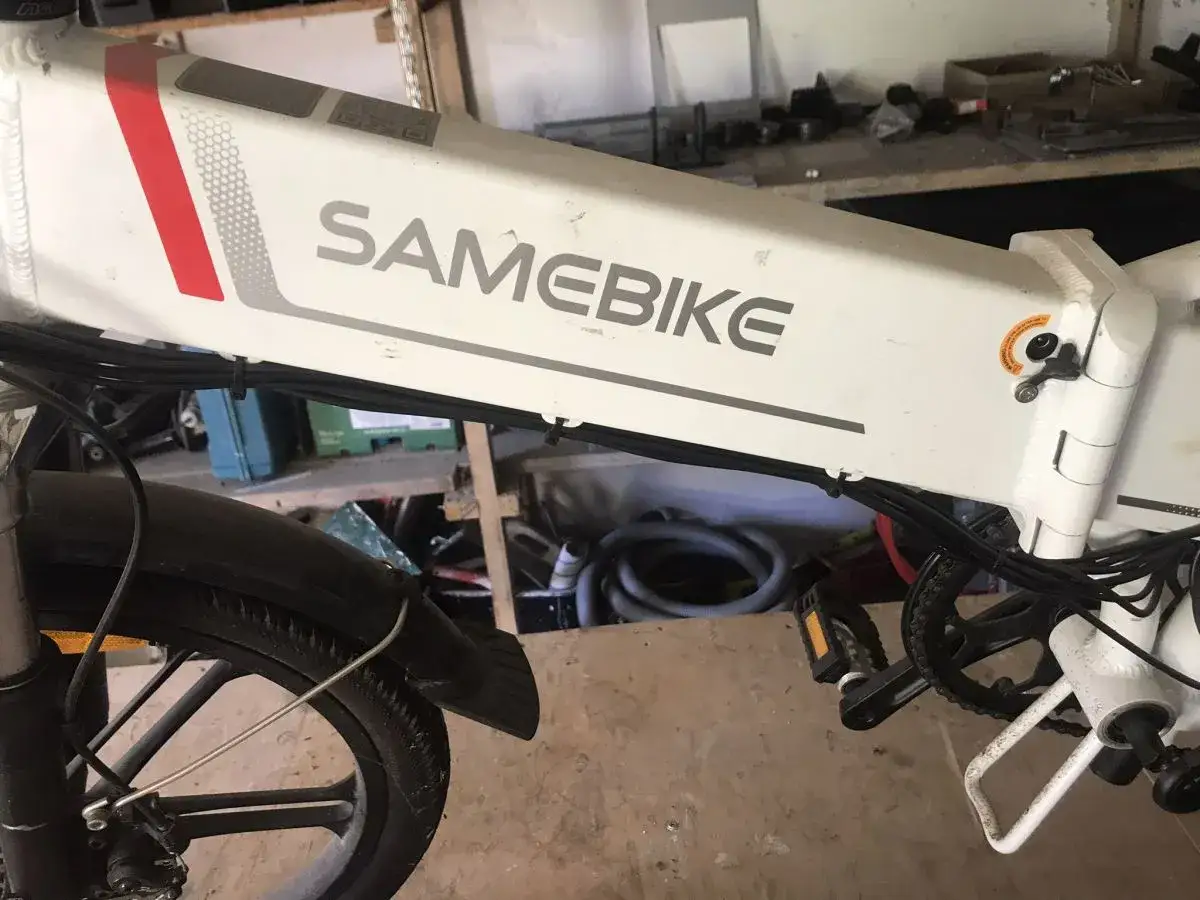 Biały rower elektryczny SAMEBIKE, z widocznym napisem marki. Wspomaganie nie działa, co jest problemem dla właściciela.