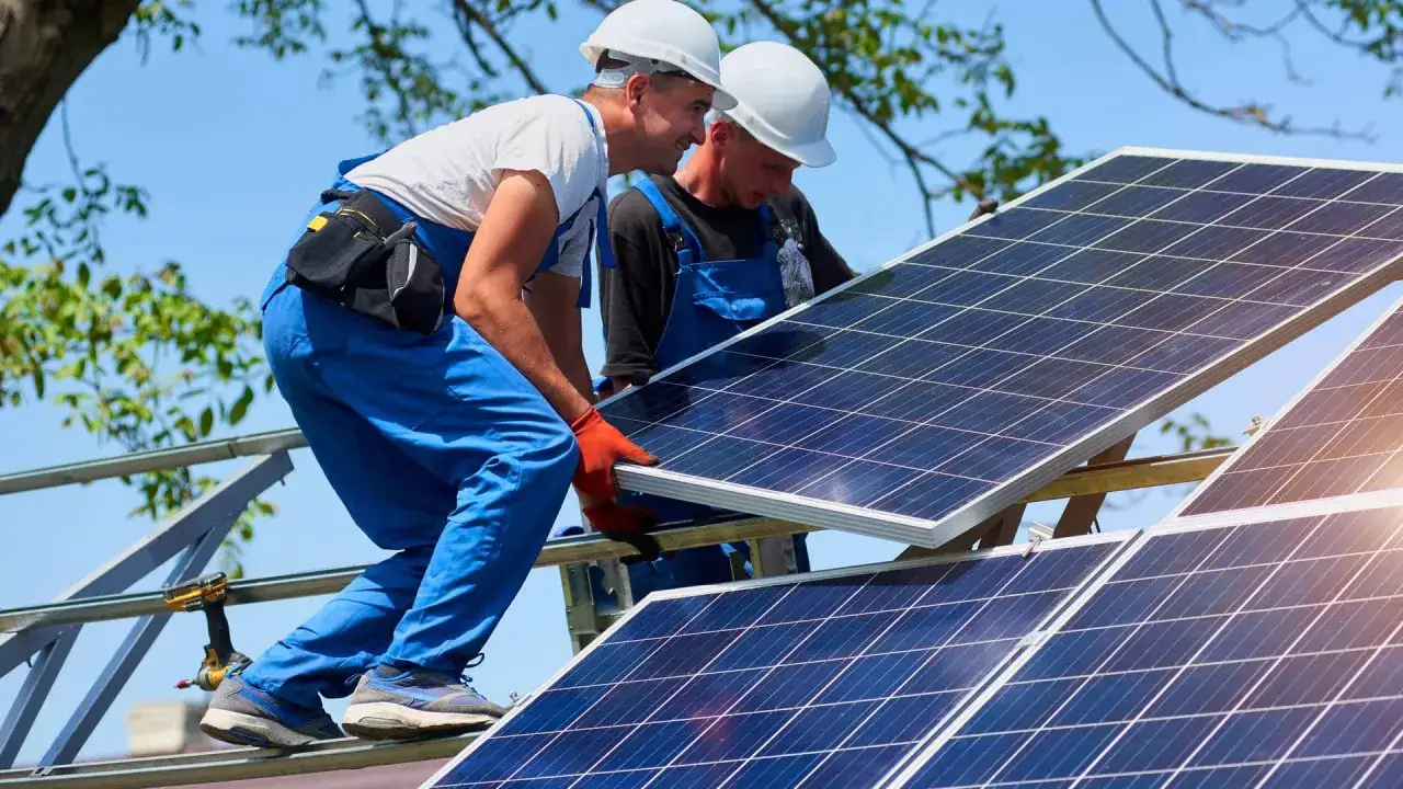 Dwóch monterów instaluje panele fotowoltaiczne. Zastanawiasz się, ile to kw? 10 kwp to moc szczytowa instalacji.
