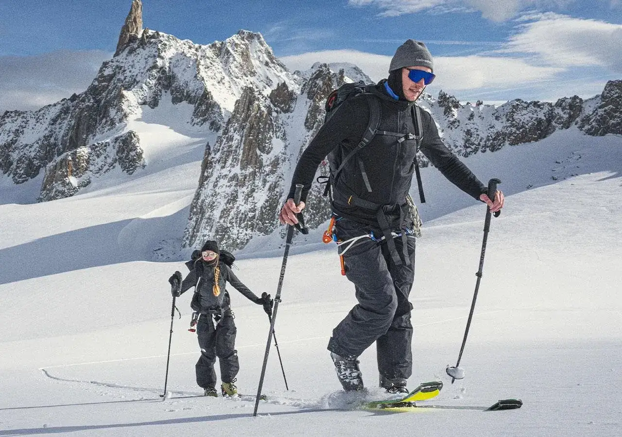 Dwóch narciarzy skiturowych w zimowych górach. Odpowiednie spodnie w góry zimą to klucz do komfortu.