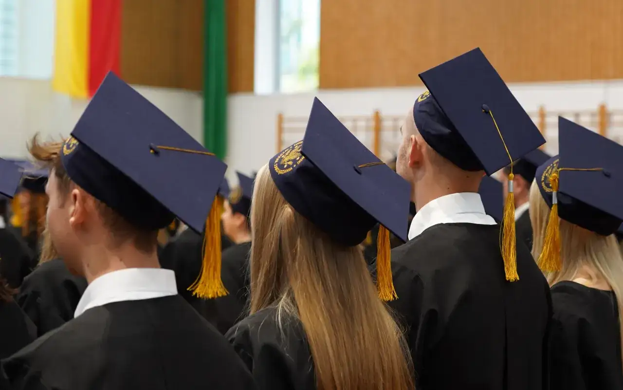 Grupa studentów w togach i biretach podczas uroczystości.