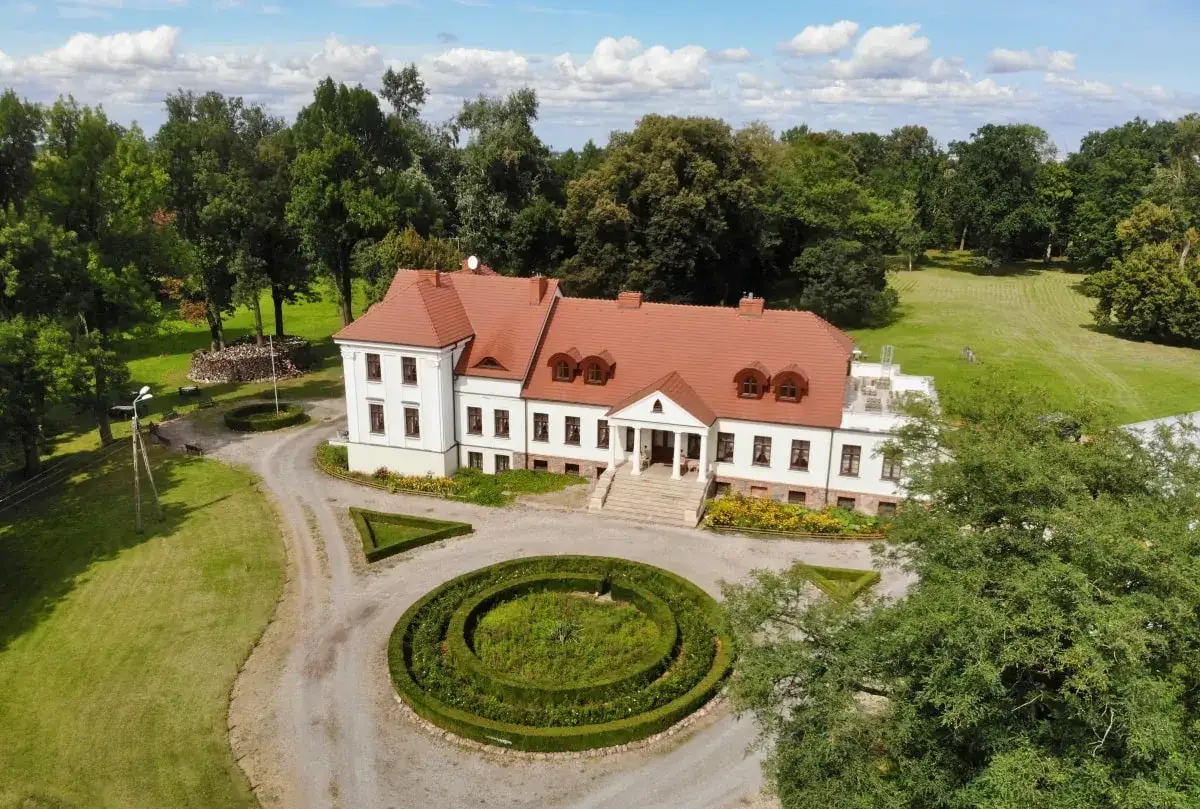 Piękny dwór stary Chotów otoczony zielenią, z zadbanym ogrodem i krętą ścieżką.