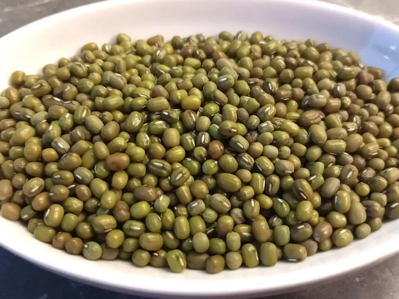 Misternie ułożona fasolka mung w białej misce. Czy fasola tuczy? Ta zielona bogactwo białka to świetny dodatek do diety.