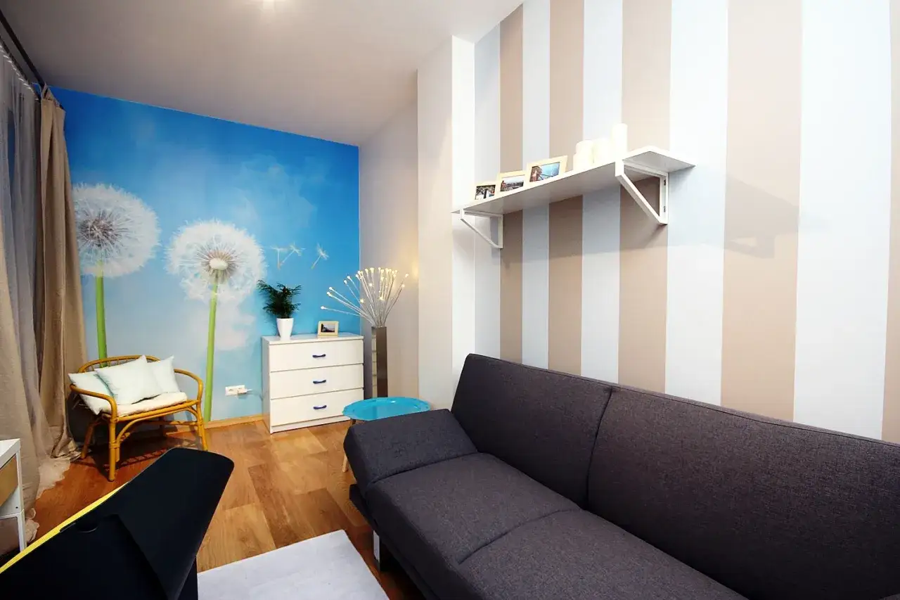 Jasne, oto propozycja:

Salon z fototapetą z dmuchawcami i asymetryczne pasy na ścianie tworzą przytulną atmosferę.